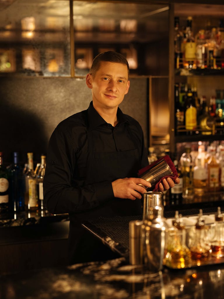 In this portrait, S.A.L.T. bartender Dawid Mroz holds a shaker behind the bar.