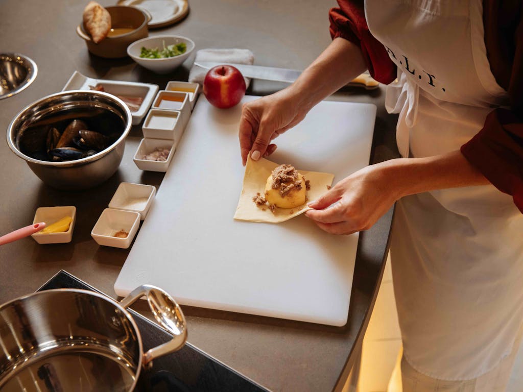 A student folds an apple pastry with cinnamon sugar in a S.A.L.T. Lab class. A fresh apple sits in the background.