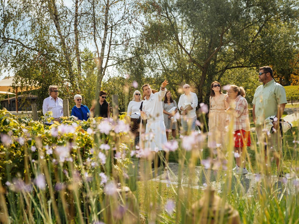 Surrounded by guests on a tour of his organic garden on a sunny day, Chef Nicolas Masse points to the distance