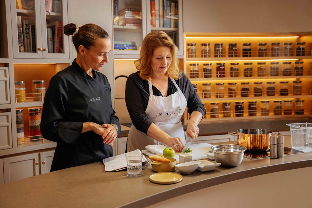 A portrait of chef-instructor Carolina Gomes wearing a black shirt and black apron in the S.A.L.T. Lab.